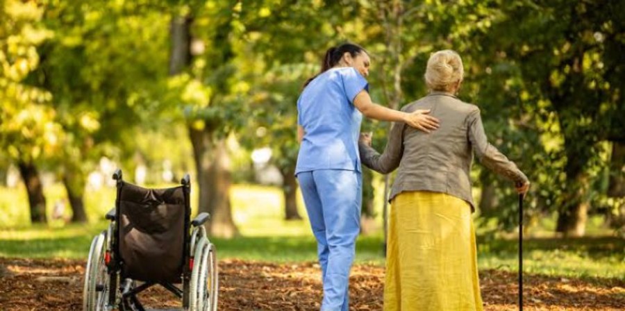 Una cuidadora acompaña a una señora mayor en una caminata por el parque